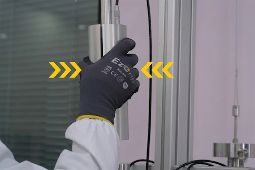 Worker confidently handling a metal pipe using EZGRIP safety gloves equipped with advanced micro-suction grip technology.