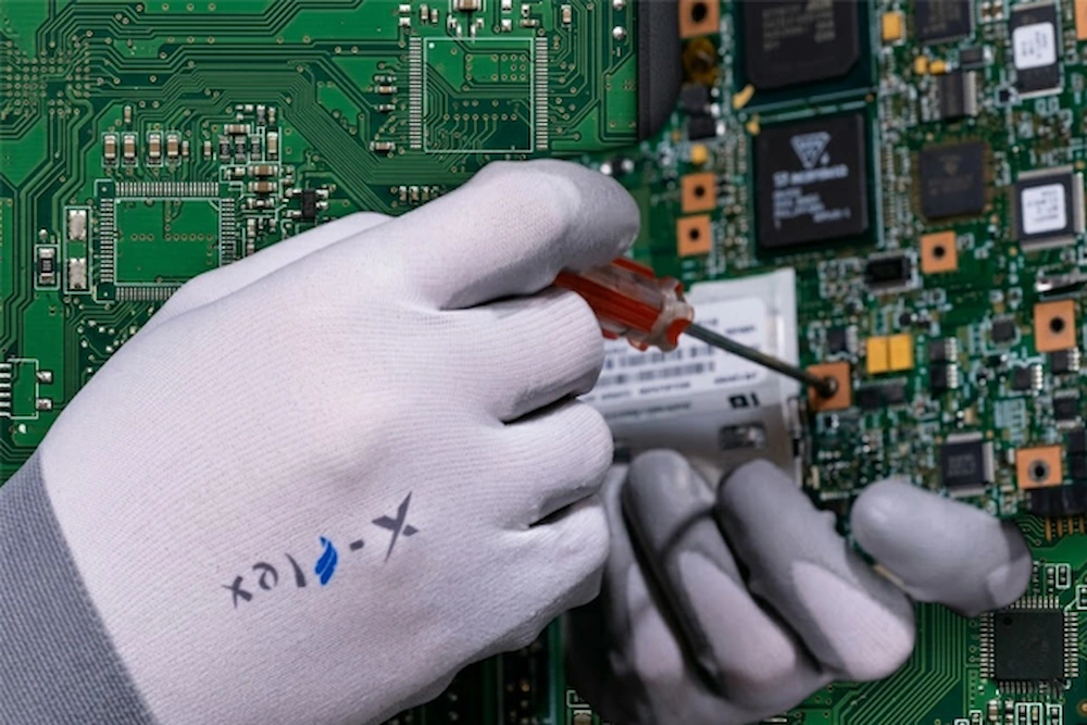 Close-up of worker wearing SQG X-FLEX 18-gauge ultra-thin safety glove precisely holding a tiny screw, showcasing extreme tactile sensitivity.
