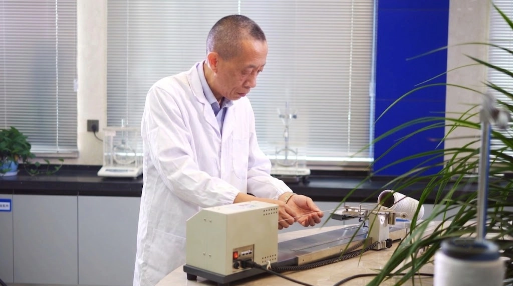 SQG industrial technician testing cut resistant glove core yarn tensile strength in laboratory environment